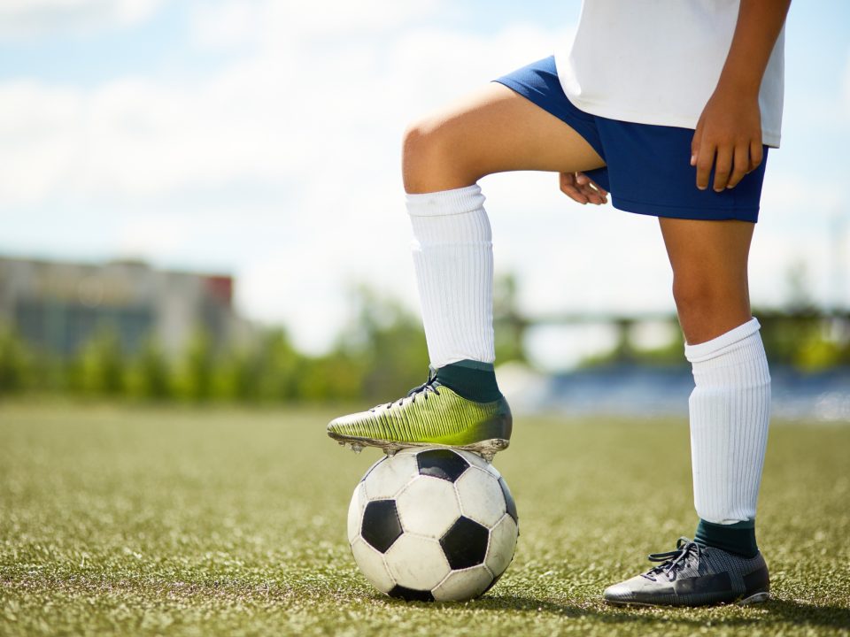 Soccer player standing with foot on top of ball