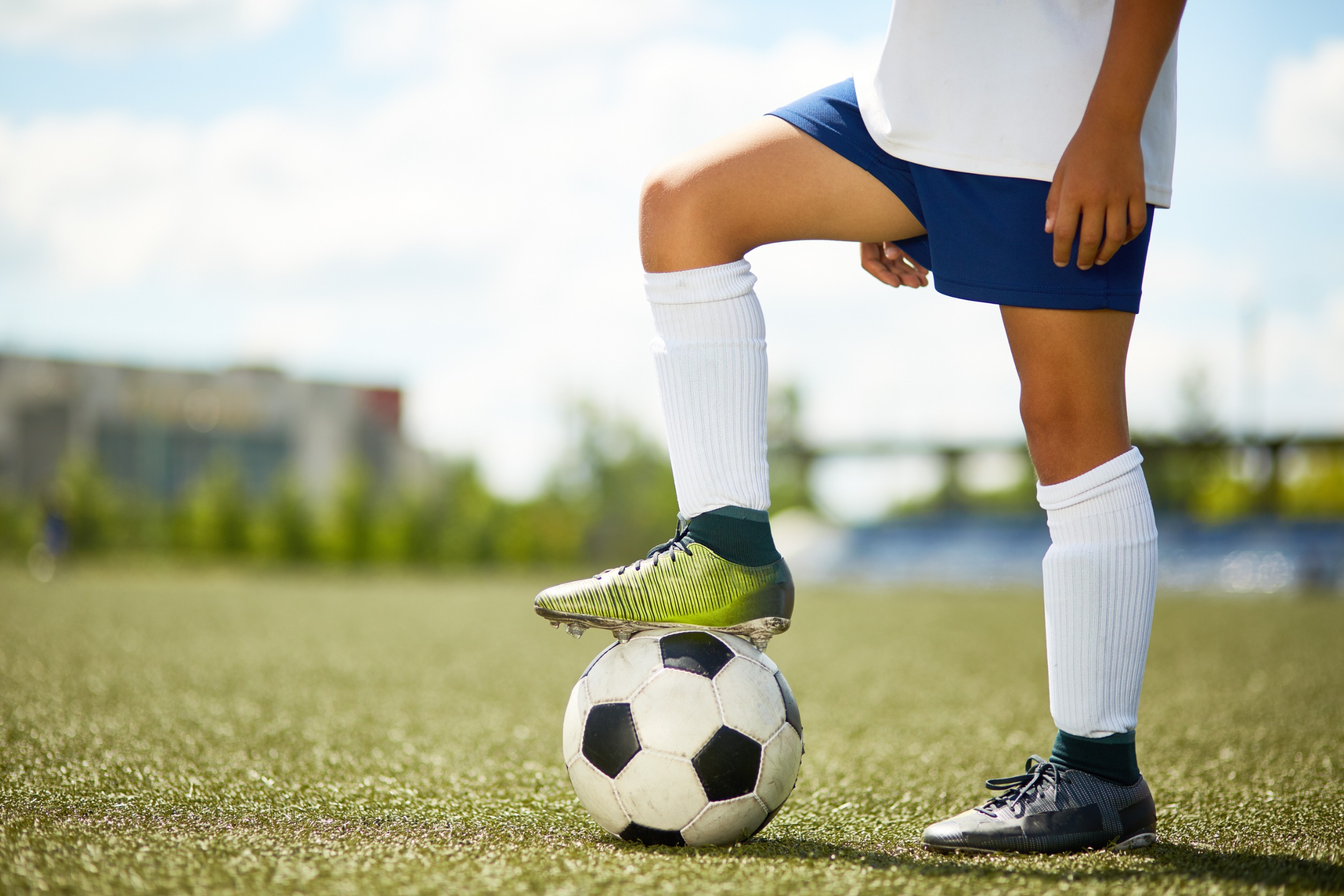 Soccer player standing with foot on top of ball